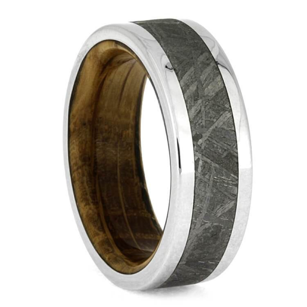 This whiskey oak wood ring is made with polished titanium and features an intricate meteorite inlay. Oak wood used in whiskey aging barrels lines the sleeve of this handmade ring. Show off a stellar style with this masculine space ring.