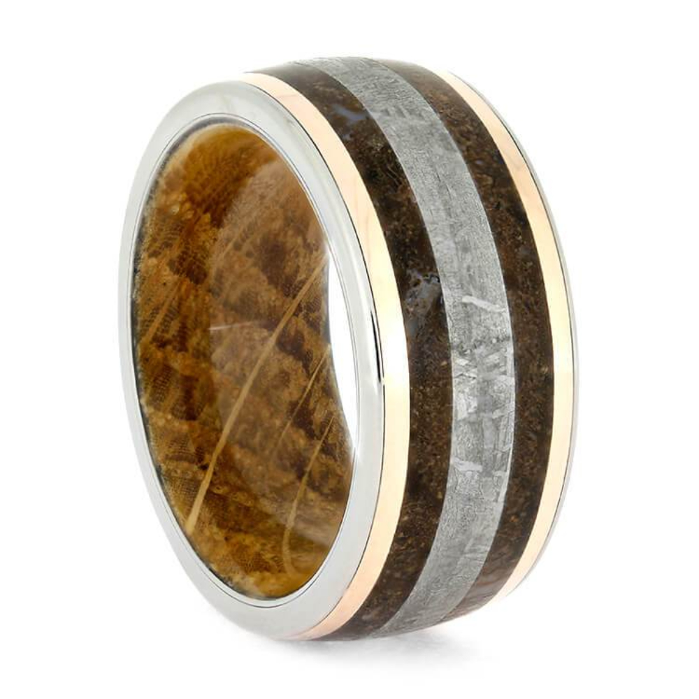  This rose gold fossil ring is adorned with exotic, colorful materials. Earthy fossil bands surround a central inlay of Gibeon meteorite. In addition, this handmade ring’s sleeve is crafted with oak wood used in whiskey aging barrels. Since this titanium ring is made with unique, natural materials, the color of each inlay will vary slightly from the ring shown here. This dinosaur bone wedding band is perfect for those who love stunning handmade rings.